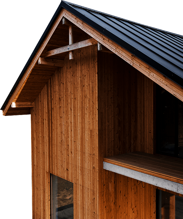A corner view of a modern wooden house with a steep black metal roof and large windows, showcasing warm wood texture.