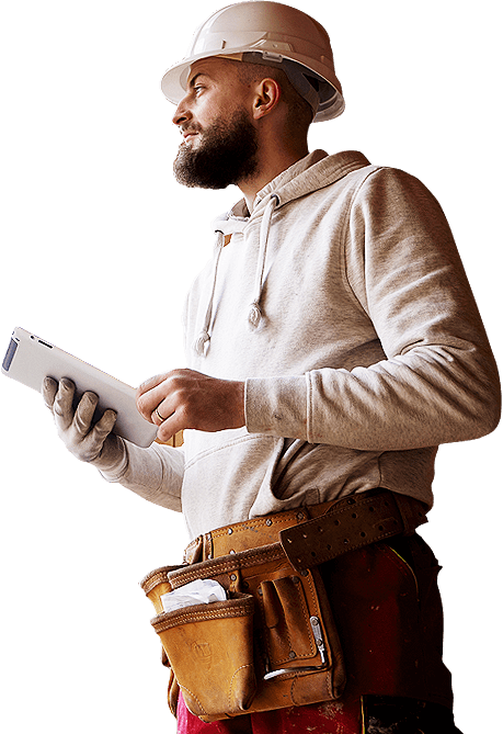 A construction worker in a gray hoodie and hard hat holds a tablet, wearing a tool belt with various tools attached.